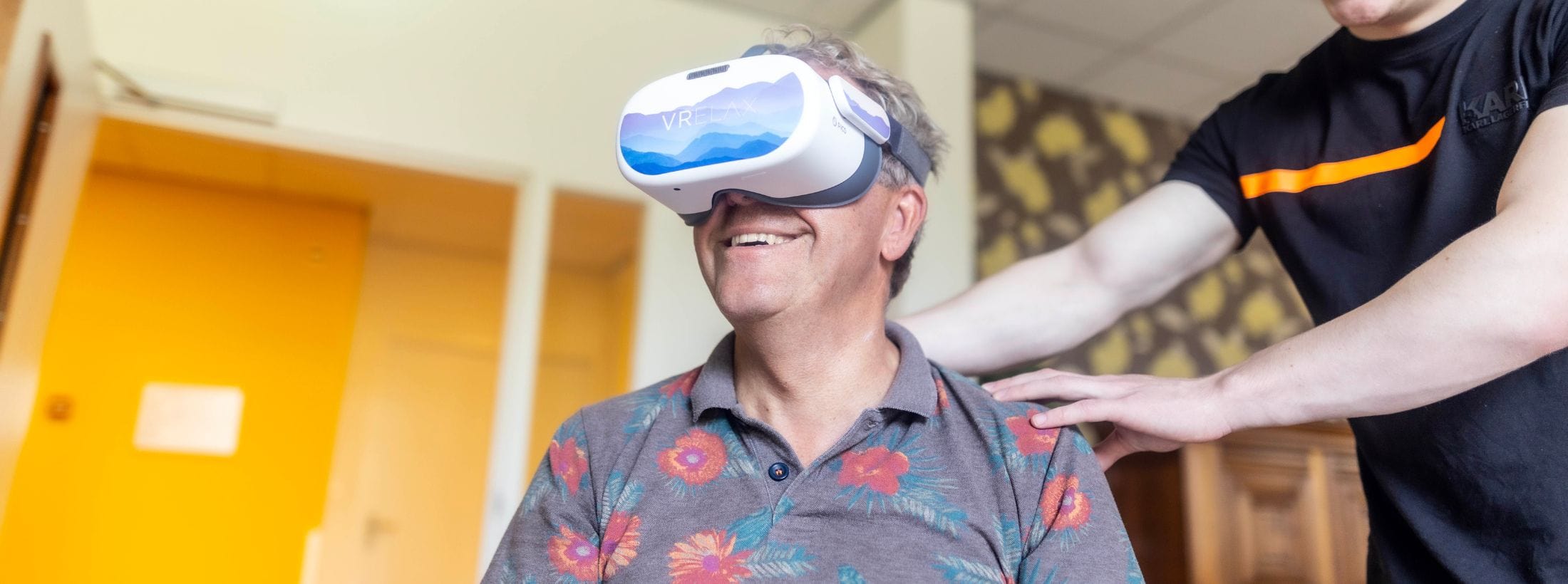 Man met een VR-bril wordt begeleid door een medewerker.