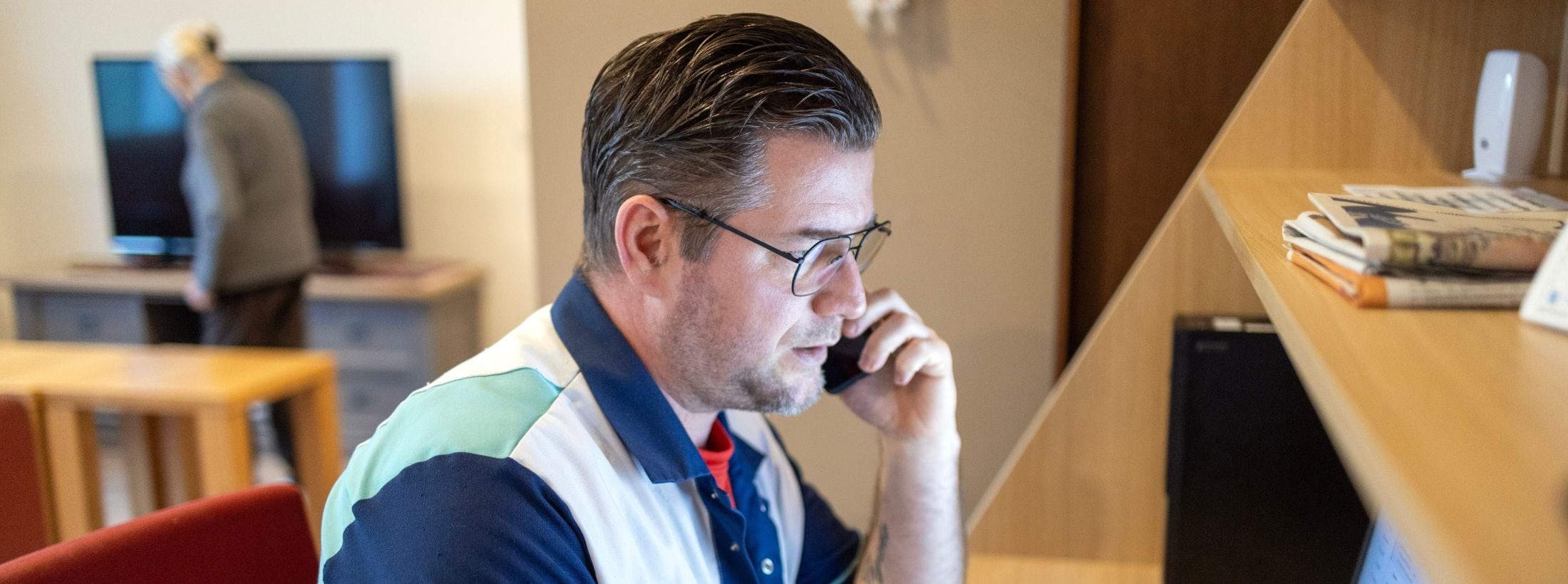 Zorgmedewerker zit achter een computer en voert een telefoongesprek.