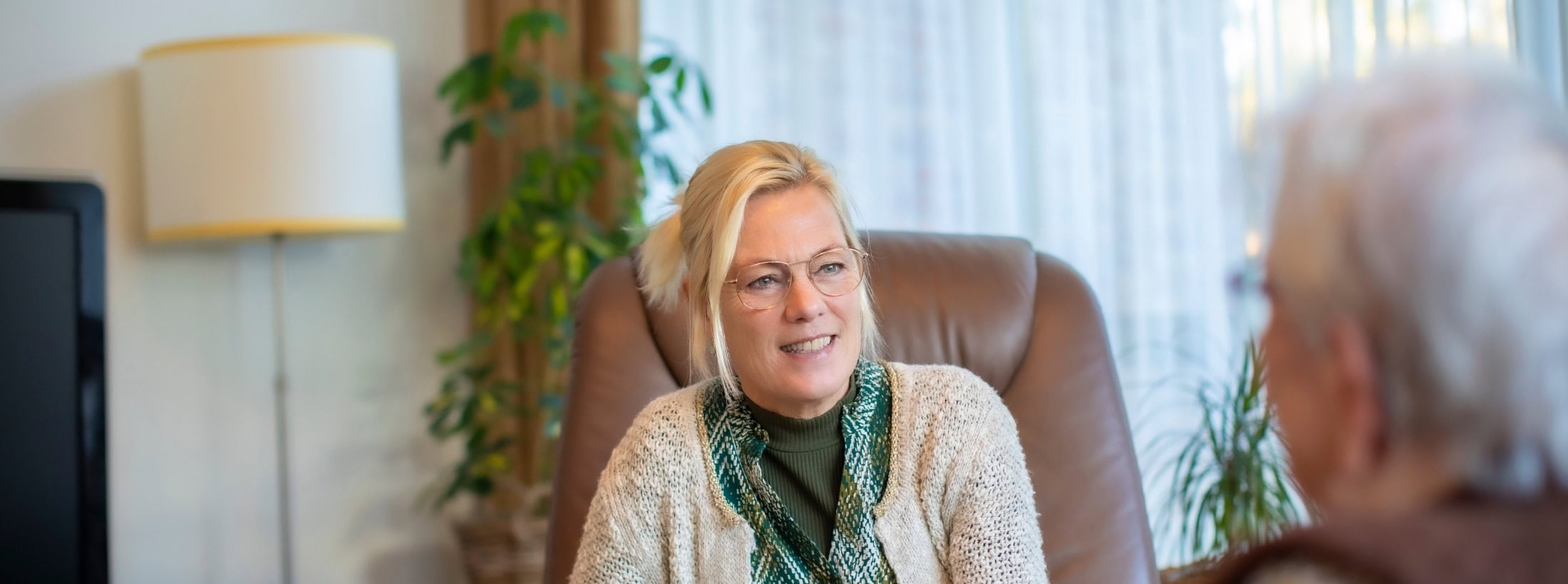 Zorgmedewerker zit tegenover een cliënt en is in gesprek.
