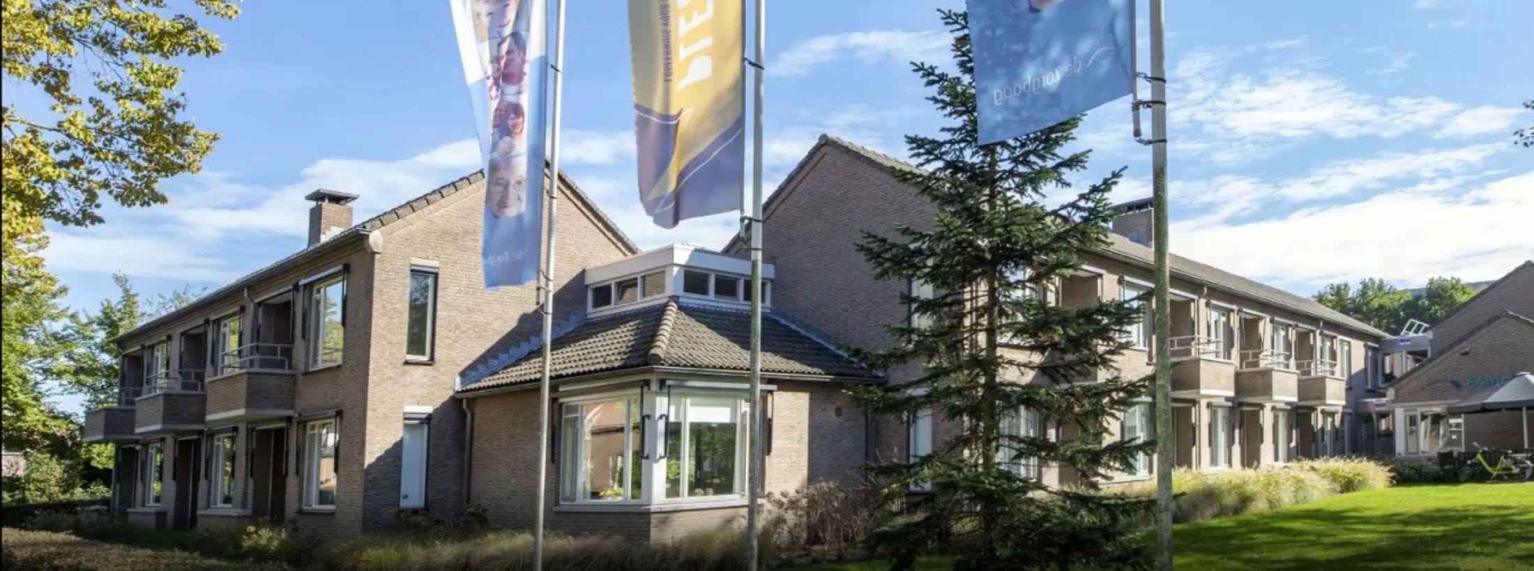 Buitenaanzicht van Logeerhuis Plezant met drie wapperende Zorgboog vlaggen.