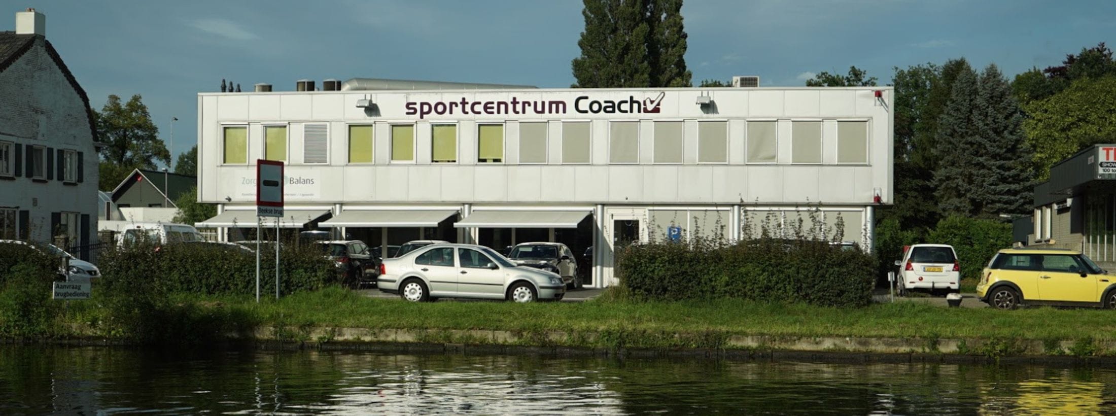 Buitenaanzicht van sportschool Have Fun Fitness met kanaal ervoor.