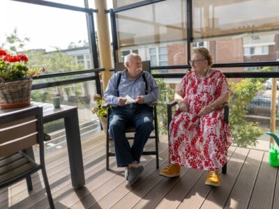 Twee cliënten, man en vrouw, zitten naast elkaar op een balkon.