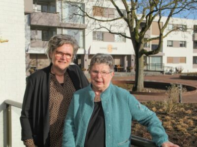 Welzijnscoach en cliënt poseren samen buiten locatie Zonnetij.