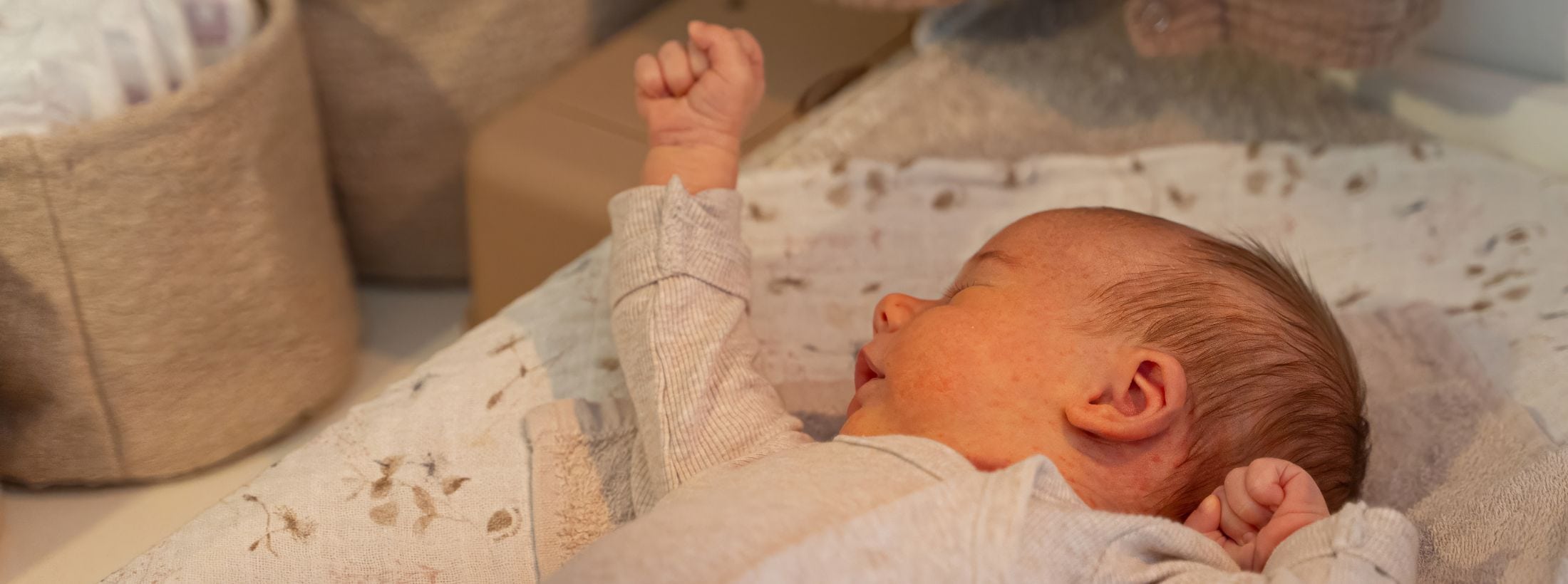 Pasgeboren baby ligt rustig op een kleedje met de ogen gesloten.