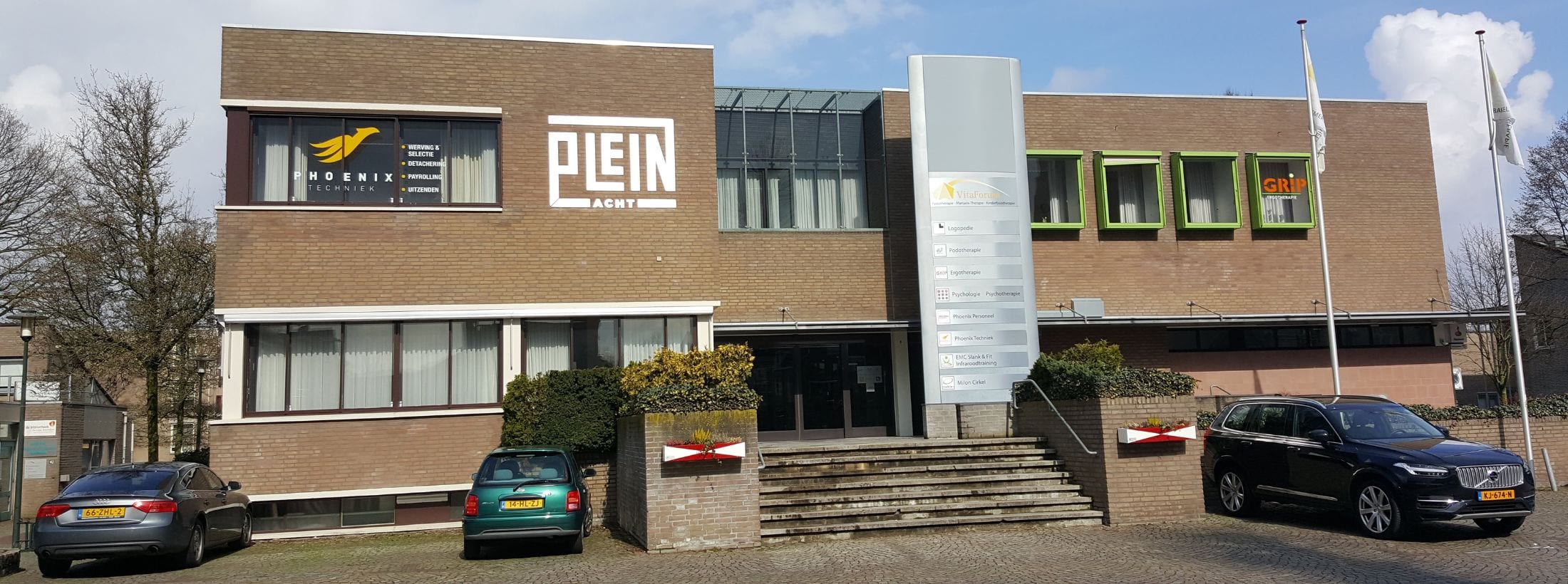 Buitenaanzicht van locatie Vitaforum met auto's bij de ingang.
