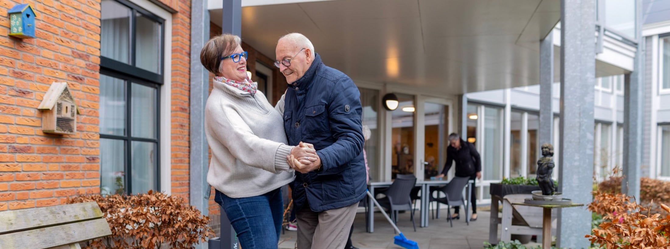 Man en vrouw dansen vrolijk samen buiten bij een locatie van Zorgboog.