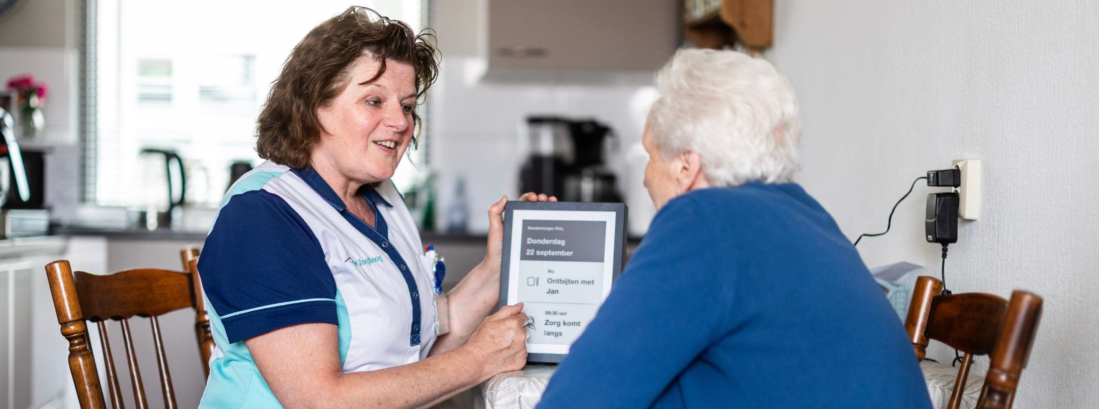 i-nurse geeft uitleg aan client aan de keukentafel.